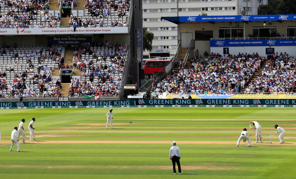 Packed cricket stadium in India with national flag on the pitch